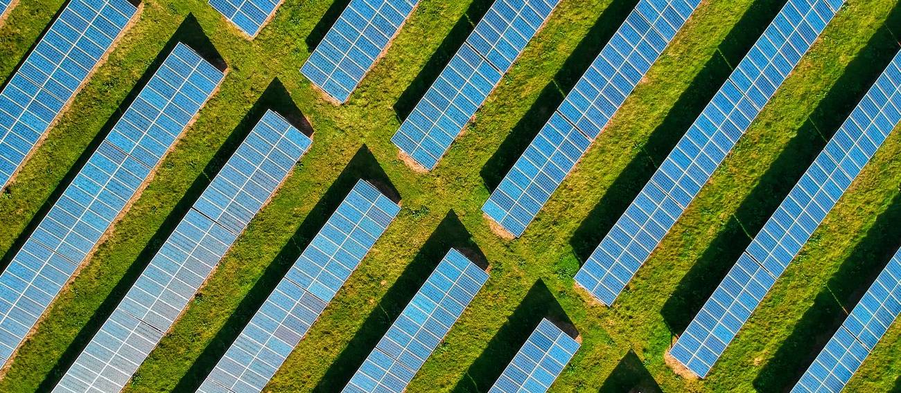 Luftbild einer Freifl&auml;chen-Solaranlage mit Gr&uuml;nfl&auml;chen zwischen den Modulreihen